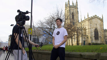 A journalism student doing a piece to camera. Another student holds the mic and works the camera.