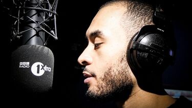 Journalism graduate Sam Moir with mic and headphones while working at BBC Radio 1Xtra