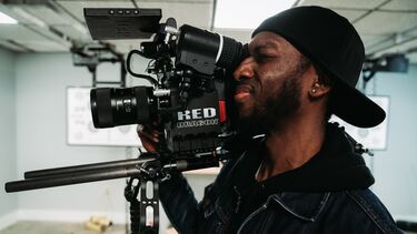 Side view of a journalist or filmmaker operating a video camera