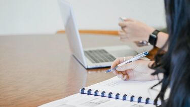 Research projects - two people one writing on a notepad, one at a laptop