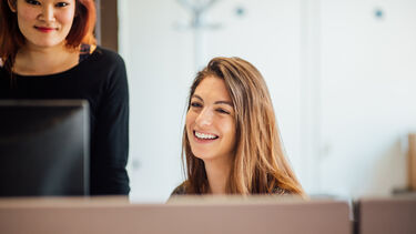 An image of students at a PC working together