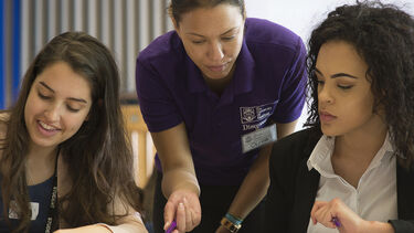 An image of a member of staff helping a student with their work.
