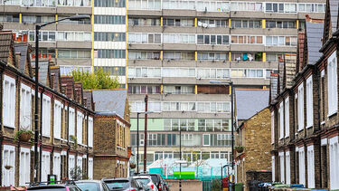 a block of flats overlooks a street with parked cars