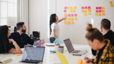 Business meeting with participants using post-its on a wall to organise ideas