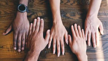 Five human hands on a wooden table