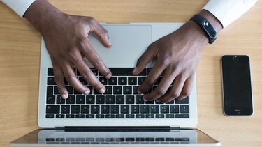 A person's hands typing on a laptop