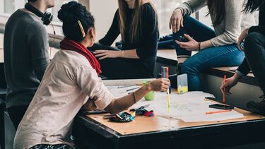 A group of people meeting in an office and writing a mind map.
