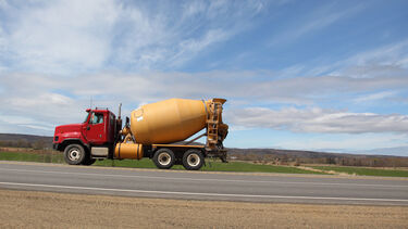 A cement truck drives on a green landscape