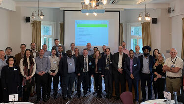Attendees of the AREC workshop stood together in front of a powerpoint presentation
