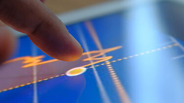 Clode-up of a finger about to touch a graph on a touch screen device.