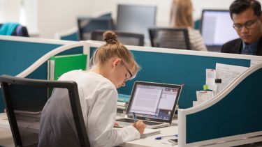 A woman working at a desk with a laptop