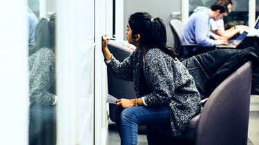 Student writing on a whiteboard in a University of Sheffield study space