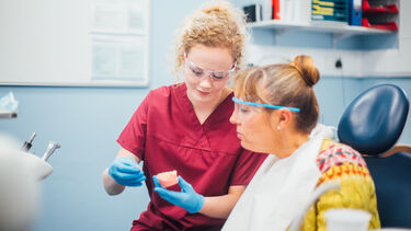 Dental student shows teeth mould to patient
