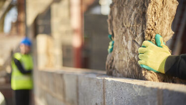 Builders holding a block of loft insulation