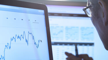 A stock image of a person looking at charts on a computer screen.