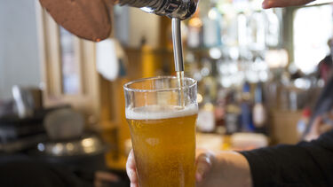A pint of beer being poured from a tap in a pub.