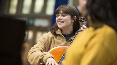 A woman playing the cello and smiling