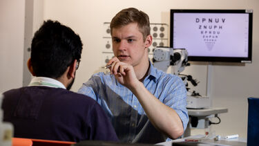 Male Orthoptics student shines torch in students eye