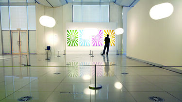 A silhouette of a man looking at a set of four graphic prints in an art gallery.