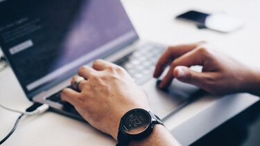 Close-up of a man's hands on a laptop keyboard