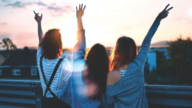 Three young women raising their hands in celebration