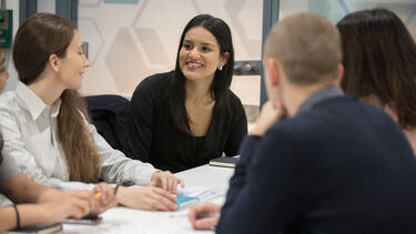 Four students stitting at a desk discussing ideas