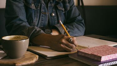 Person writing on paper in a café