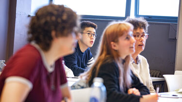 Mix of male and female students look towards front of seminar room