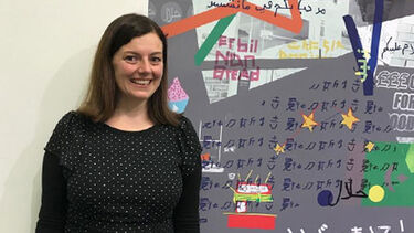 A member of staff stood alongside a multilingual poster