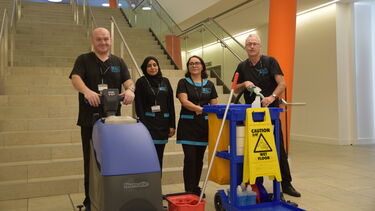 Four members of the cleaning team standing in front of some stairs