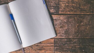 A notebook and pen on a wooden surface