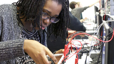 Female student using a circuit board in the Electronics lab