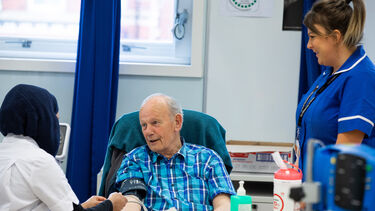 Two nurses take blood pressure of male patient 