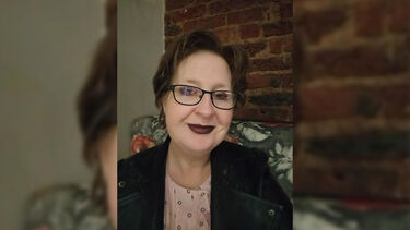 A woman in glasses sat looking at the camera