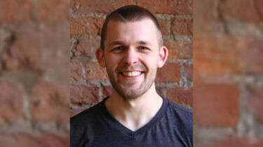 A man stood in front of a brick wall