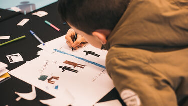 A child draws on paper while taking part in a workshop activity