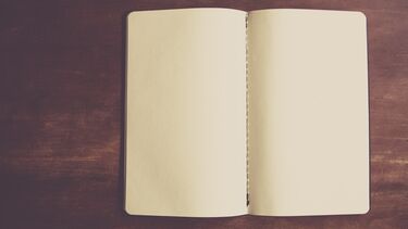 Open blank notebook on wooden tabletop 