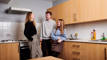 students stood in a kitchen laughing