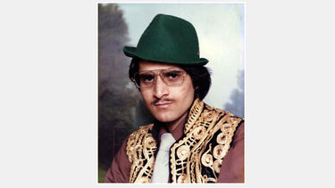 A vintage photograph of a young Asian Man wearing a mix of traditional eastern and modern western clothing