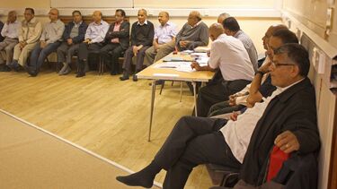 A group of men sitting around the edge of a room