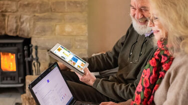 man using tablet and woman using laptop