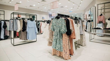 An image of the inside of a clothes shop, with racks of women's clothes.