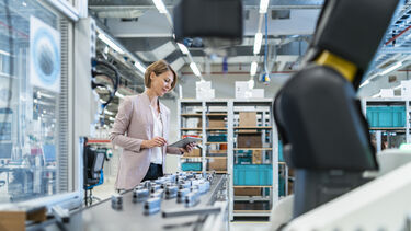 An engineer looking at a tablet next to a production line inside a factory