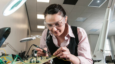 An electronics student working on a circuit board