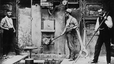 Black and white period image of men working in factory