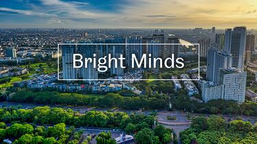The text 'Bright Minds' over a photo of the skyline of a city with green wooded areas in the foreground and towers in the background