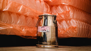 A milk churn in front of stacks of plastic bottles