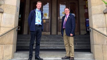 Two male staff stand in front of Firth Court entrance