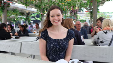 Female student sat on bench smiling at camera