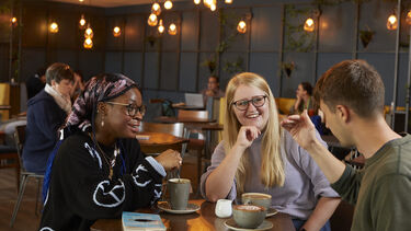 Three Sheffield students drinking coffee in Coffee Revolution